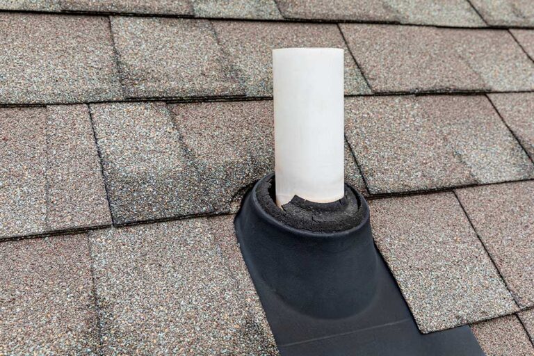 Workers protect a shingled roof with secured coverings while renovating a two-story home.