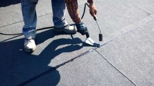 A homeowner examines dark roof streaks and a ceiling water stain with a flashlight.